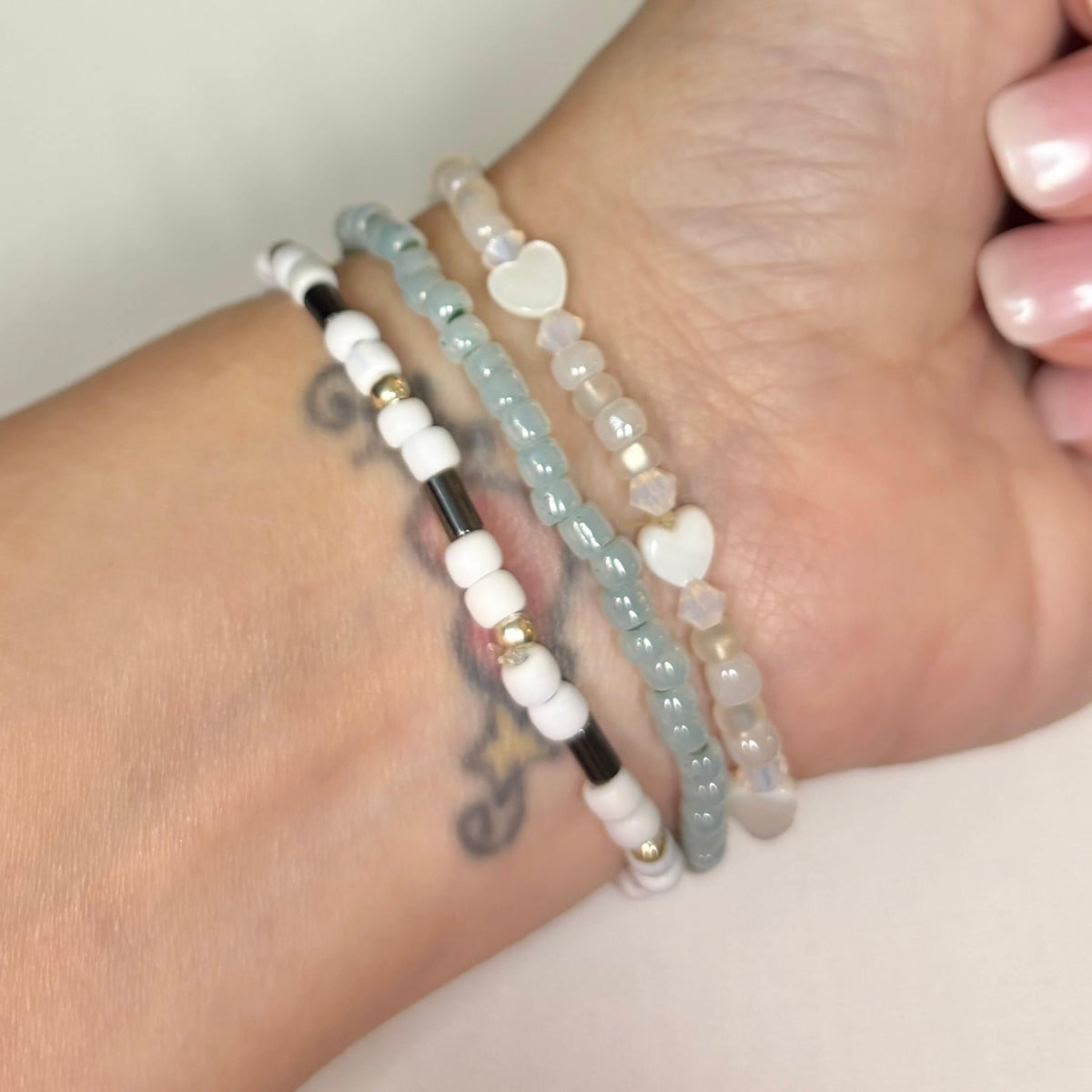 Blue and white Joy bracelet stack with silver accents, hematite details and shell heart beads worn on wrist.