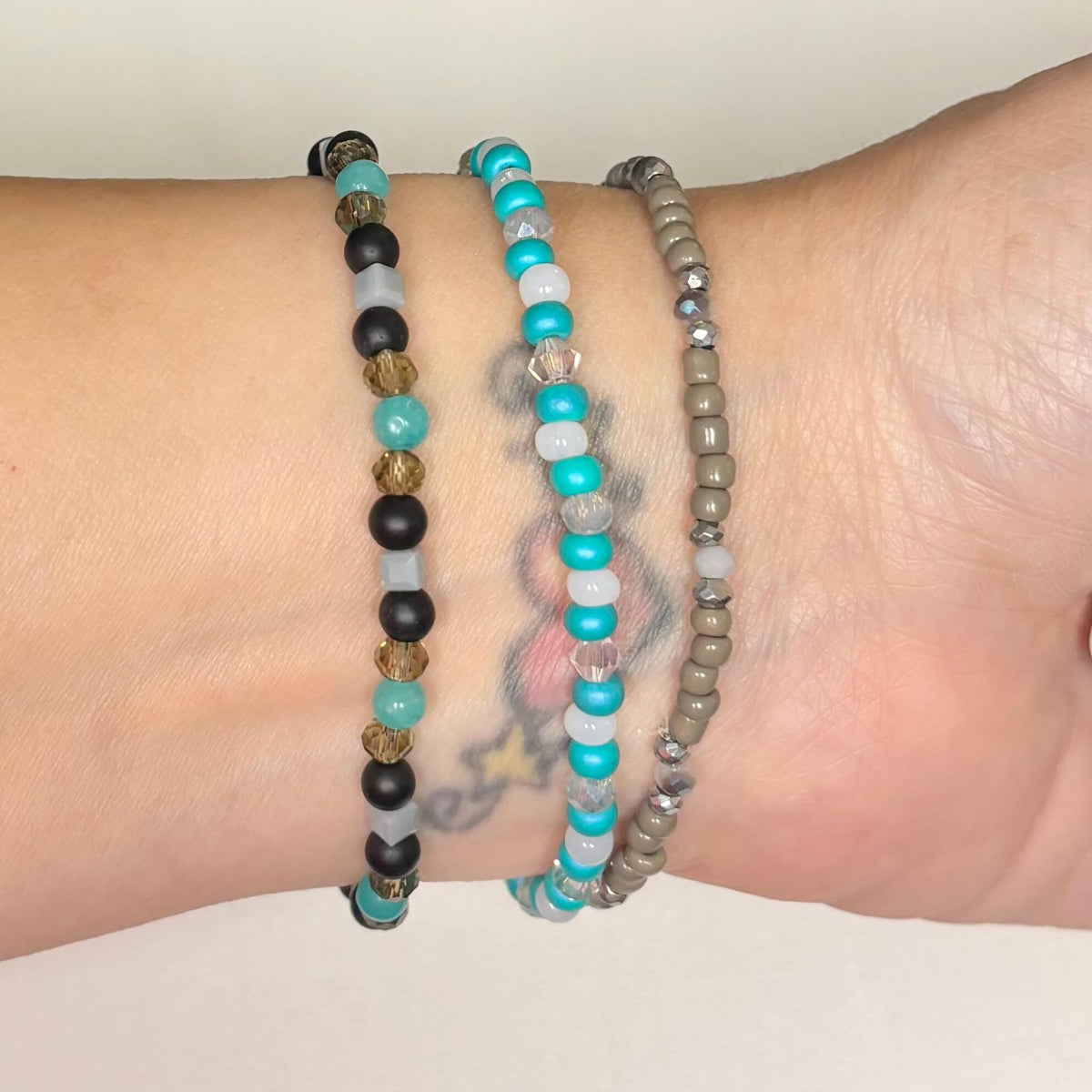 Handmade turquoise and neutral bracelet stack with evil eye and black bead accents.